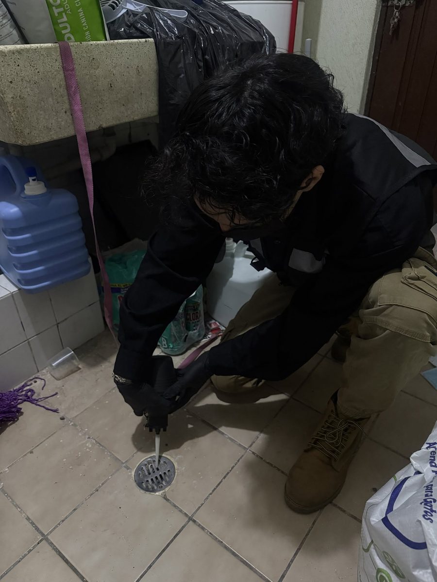 Técnico de FUMITECT aplicando polvo insecticida en una coladera