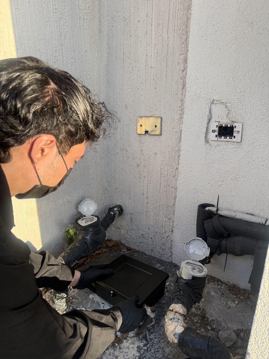 Técnico de FUMITECT colocando una estación para roedores junto a los medidores de agua